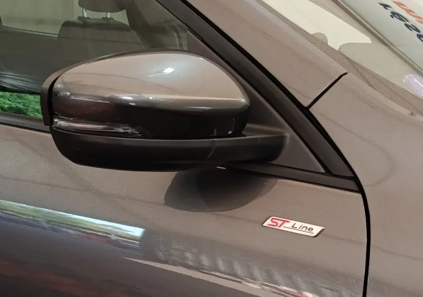 Gros plan sur le rétroviseur côté gauche et l’écusson ST-Line d’un Ford Kuga gris foncé 2023.