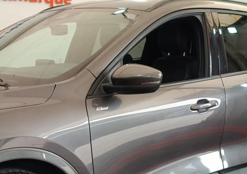 Vue latérale gauche rapprochée du Ford Kuga gris foncé avec badge ST-Line X sur l'aile avant.