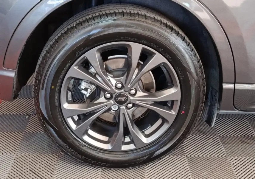 Gros plan sur la roue avant droite gris foncé du Ford Kuga 2023 avec jante alliage et logo Ford au centre.
