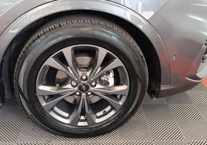 Gros plan sur la roue avant droite gris foncé du Ford Kuga 2023 avec jante alliage et logo Ford au centre.