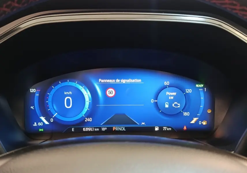 Vue du combiné d'instruments numérique bleu du Ford Kuga 2023, affichant vitesse, puissance et panneaux de signalisation.