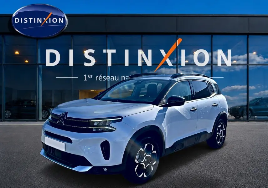 Citroën C5 Aircross blanc vue 3/4 avant droit, avec barres de toit et jantes alu distinctives.