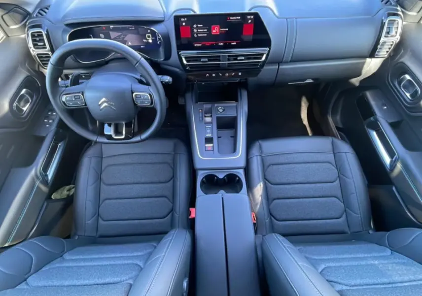Vue intérieure de face du poste de conduite du Citroën C5 Aircross 2025 avec sièges noirs et écran tactile central.