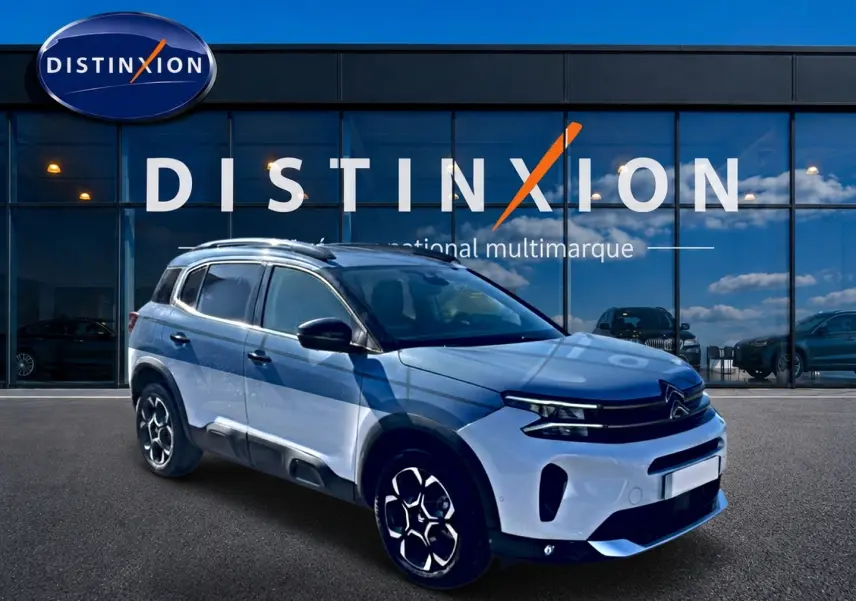 Citroën C5 Aircross blanc vue 3/4 avant droit, avec barres de toit et jantes alu distinctives.