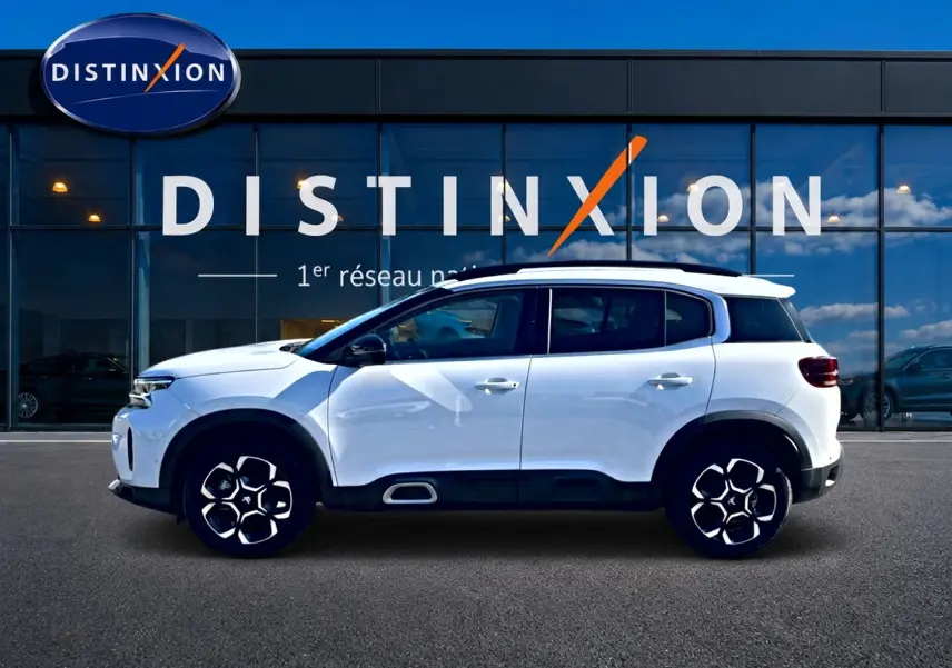 Profil droit d'un Citroën C5 Aircross blanc 2025 avec jantes alu distinctives et barres de toit noires.