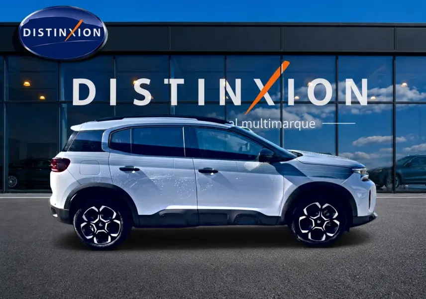 Profil droit du Citroën C5 Aircross blanc 2025 avec jantes alu et barres de toit devant vitrine Distinxion.