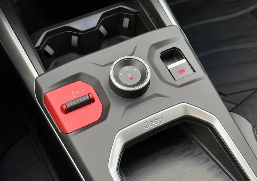 Vue rapprochée de la console centrale du Jeep Compass 2026, avec molette de boîte auto et bouton rouge Select Terrain.