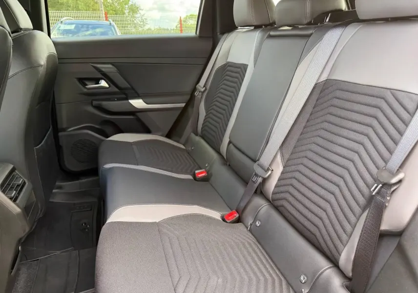 Vue latérale intérieure des sièges arrière gris et noirs du Jeep Compass 2026 avec ceintures de sécurité visibles.