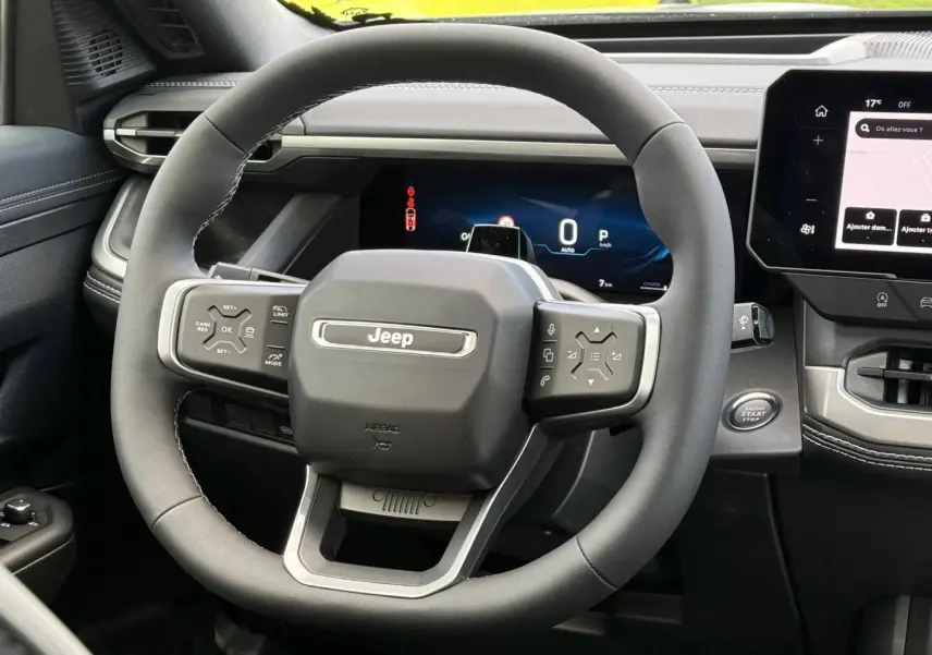Vue rapprochée du volant Jeep Compass 2026 en cuir noir avec commandes intégrées et tableau de bord numérique.