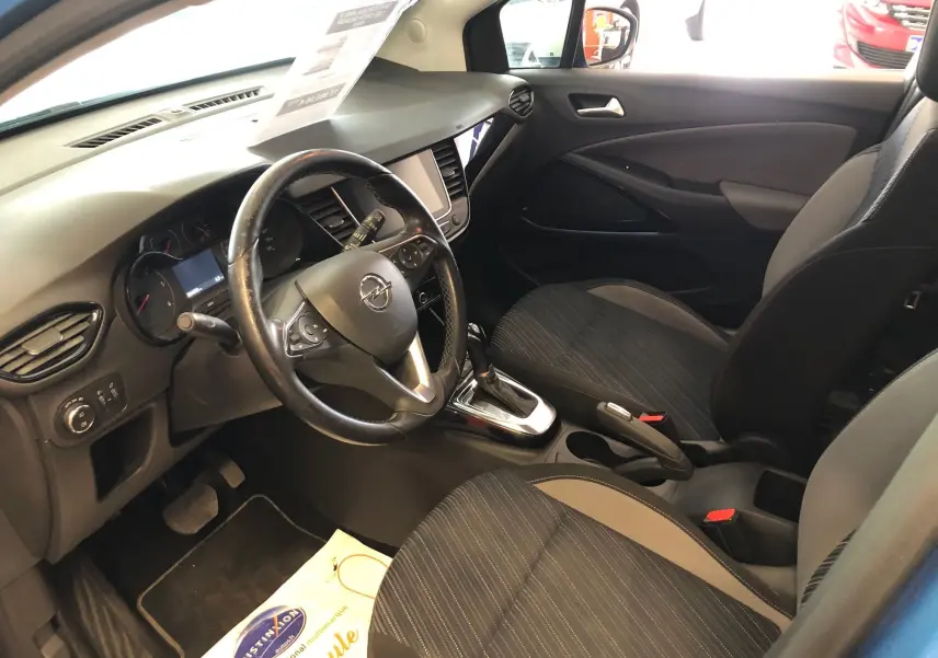 Intérieur de l'Opel Crossland X bleu intens métal vu côté conducteur, avec tableau de bord et sièges noirs en tissu.
