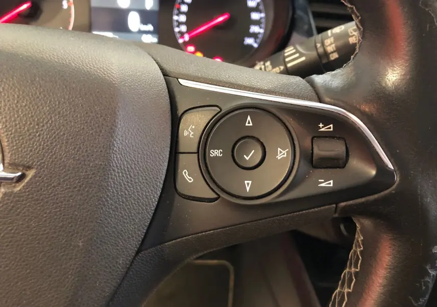 Gros plan sur les commandes du volant côté gauche d'un Opel Crossland X 2019 au cuir noir avec boutons multifonctions.