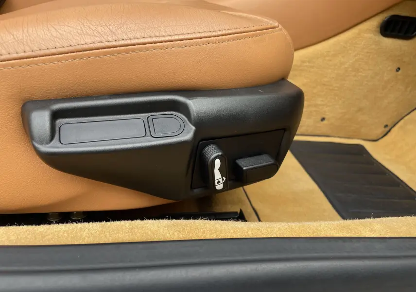 Gros plan sur les commandes de réglage du siège cuir beige d'une Maserati Spyder gris Nuvolari de 2002.