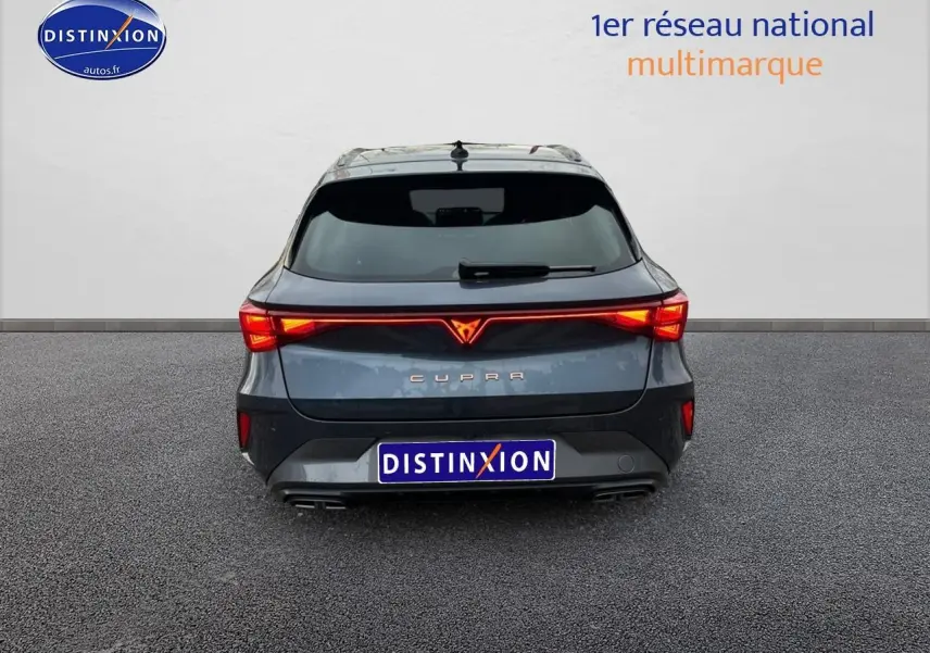 Vue arrière d'une CUPRA LEON ST gris magnétique avec feux LED allumés et double sortie d'échappement visible.