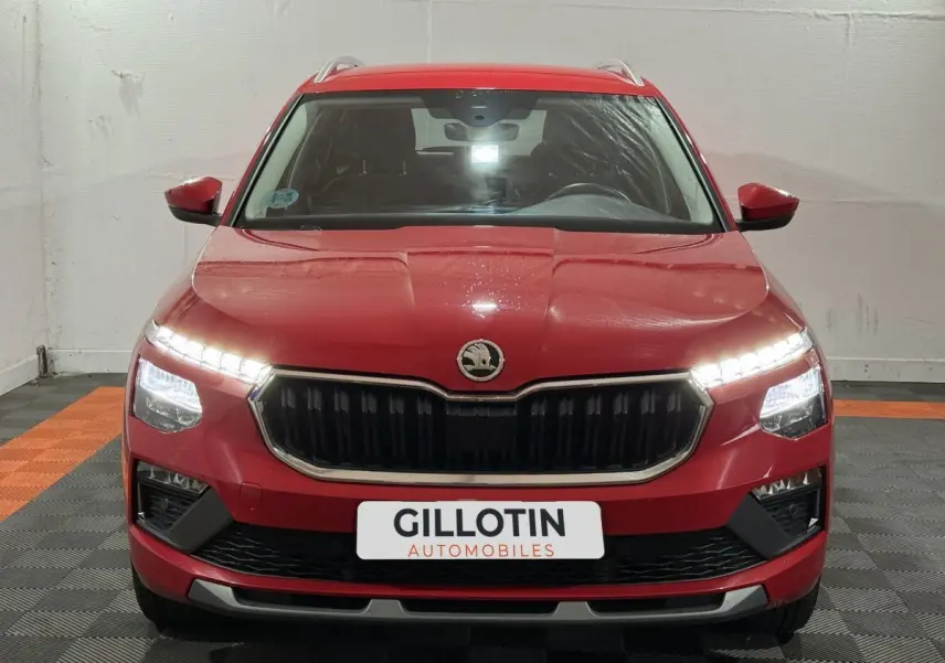 Vue frontale d'un Skoda Kamiq rouge 2024 avec phares LED allumés et calandre noire distinctive.
