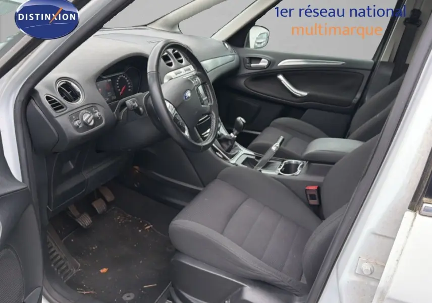 Intérieur avant droit du Ford S-MAX blanc 2013, montrant les sièges noirs, le volant et la boîte manuelle.