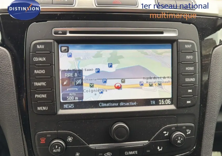Vue rapprochée du tableau de bord du Ford S-MAX blanc de 2013, mettant en valeur l’écran GPS et les commandes de climatisation.