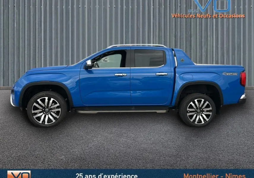 Vue de profil côté gauche du pick-up Volkswagen Amarok Simple Cabine bleu avec jantes alliage 21 pouces et marchepieds visibles.