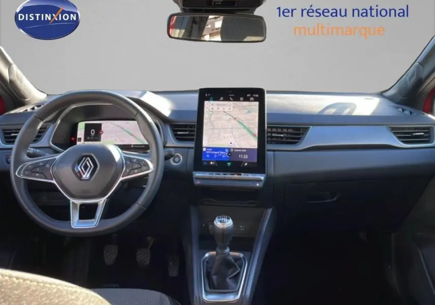 Vue intérieure frontale du tableau de bord du Renault Captur rouge 2025 avec écran tactile vertical et boîte manuelle.