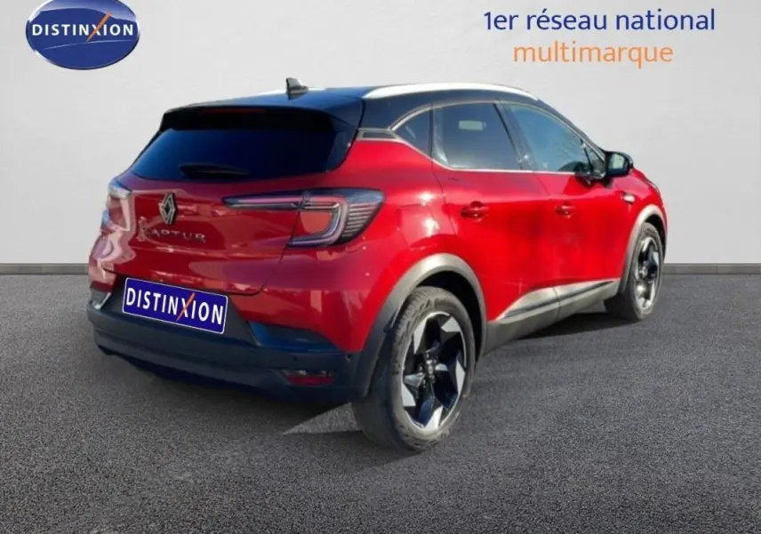 Vue 3/4 arrière droite d'un Renault Captur rouge 2025 avec jantes aluminium et toit noir contrasté.