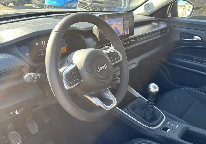 Vue intérieure côté conducteur du Jeep Avenger 2025 avec volant, boîte manuelle et écran tactile central.