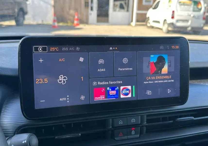 Écran tactile central affichant la climatisation et les radios favorites dans un Jeep Avenger gris, vue intérieure frontale.