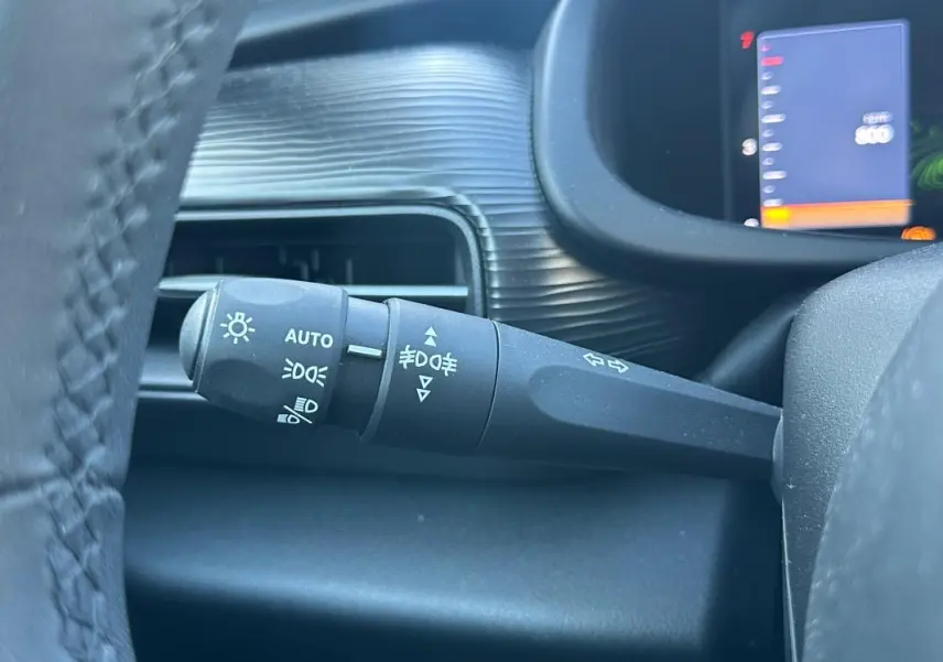 Gros plan sur la commande des phares et clignotants à gauche du volant dans l'habitacle gris du Jeep Avenger 2025.