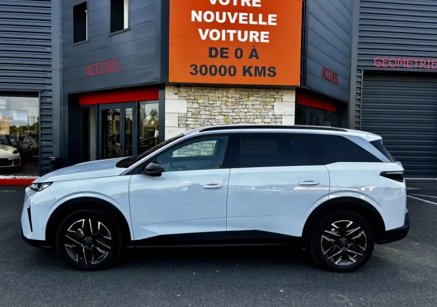 Profil côté gauche du Peugeot 5008 blanc hybride 2025, avec jantes noires et toit contrasté noir.