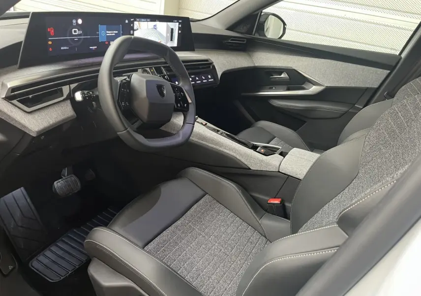Vue intérieure côté conducteur du Peugeot 5008 Hybrid 2025, volant cuir multifonctions et tableau de bord digital large.