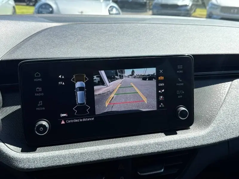 Écran tactile intérieur montrant la caméra de recul d'une Skoda Scala bleu, avec affichage des aides au stationnement.