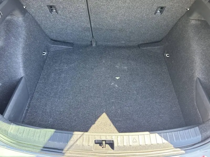 Vue plongeante sur le coffre vide gris foncé de la Skoda Scala 1.0 TSI Evo2 116ch, avec tapis en tissu et fixations visibles.