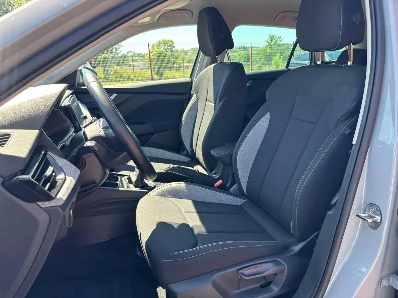Vue intérieure côté conducteur de la Skoda Scala 2025, sièges tissu noir et gris, volant cuir multifonction visible.