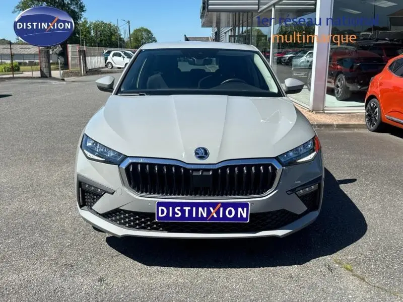 Vue avant d'une Skoda Scala blanche avec calandre chromée et phares LED, stationnée devant un showroom.
