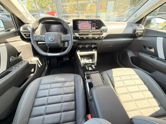 Vue intérieure avant de la Citroën C4 2025 essence gris foncé, avec tableau de bord numérique et écran tactile central.