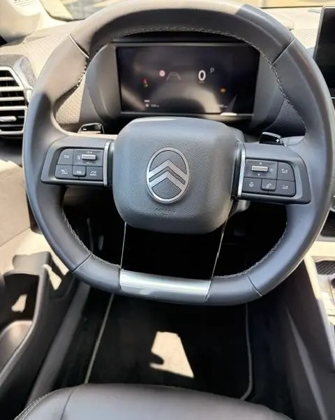 Vue rapprochée du volant cuir noir multifonctions de la Citroën C4 Essence 130 EAT8 MAX avec tableau de bord numérique.