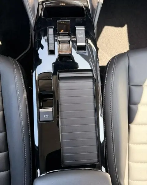 Vue plongeante sur la console centrale noire brillante de la Citroën C4 Essence 130 EAT8 MAX, avec commandes de boîte auto et frein électrique.