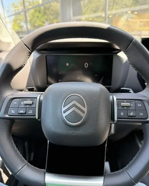 Vue rapprochée du volant cuir multifonctions noir de la Citroën C4 2025 avec logo central et commandes intégrées.