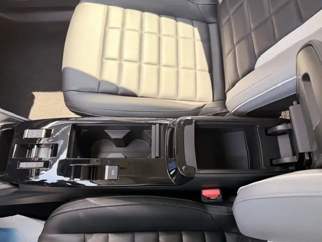 Vue rapprochée de la console centrale noire et des sièges bicolores beige et gris foncé de la Citroën C4 2025.