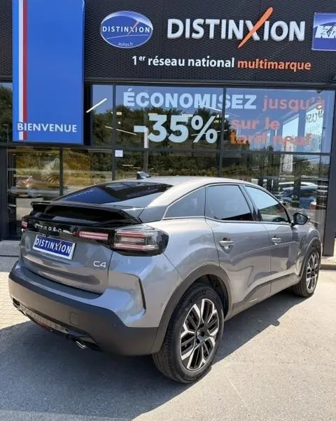 Vue 3/4 arrière droite d'une Citroën C4 gris foncé avec toit noir, feux arrière LED et jantes alliage distinctives.