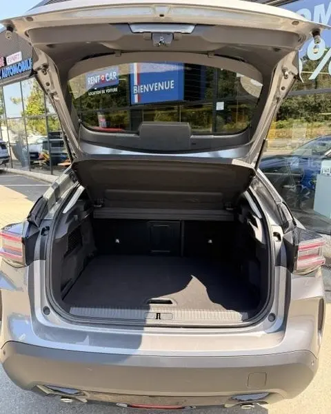 Coffre ouvert vu de l'arrière d'une Citroën C4 gris foncé, montrant un espace de chargement spacieux et propre.