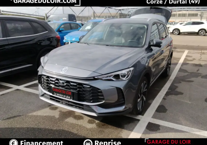 MG ZS 1.5L Hybrid+ Luxury gris clair vu en 3/4 avant droit sur parking avec calandre noire distinctive.