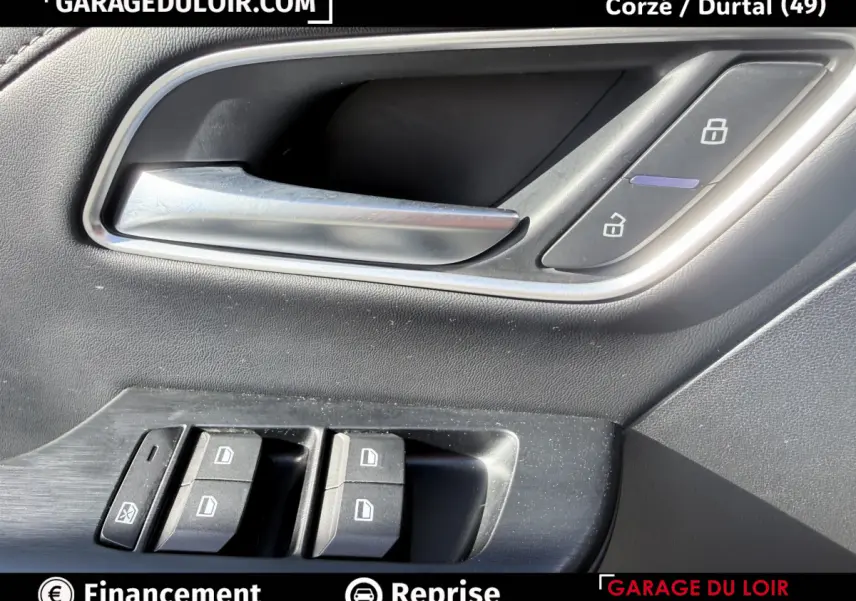 Gros plan sur la poignée intérieure et les commandes de porte côté conducteur d’un MG Motor ZS gris clair.