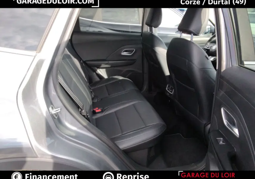 Vue intérieure arrière côté droit du MG Motor ZS gris clair 2025, sièges en cuir noir et accoudoir central visible.