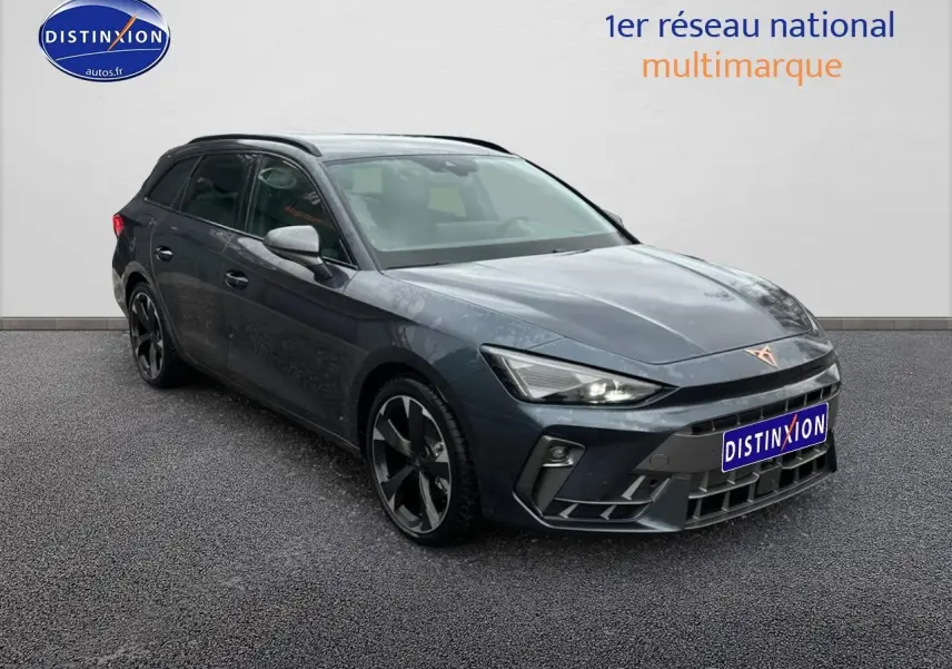 Vue 3/4 avant gauche d'une CUPRA LEON ST gris magnétique avec jantes alliage et barres de toit visibles.