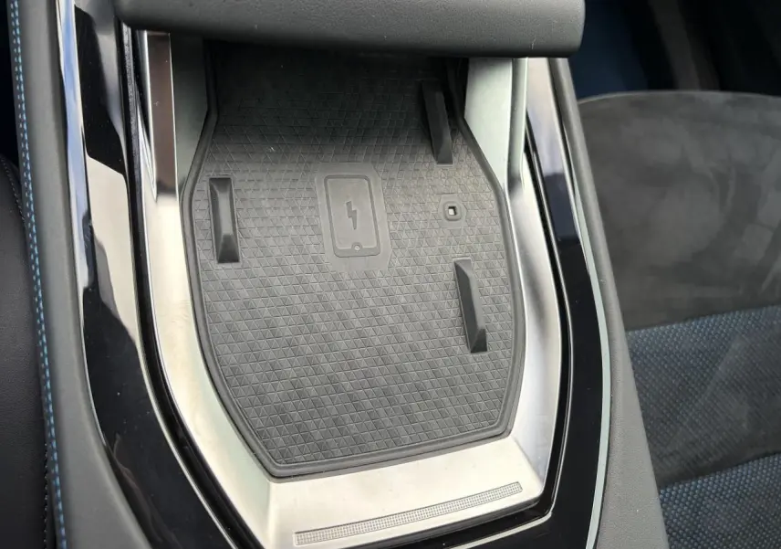 Gros plan sur la console centrale noire avec surface de recharge sans fil et surpiqûres bleues du siège Renault Rafale Summit Blue.