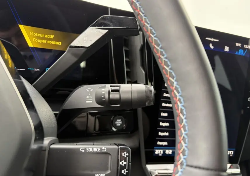 Détail intérieur du levier de vitesses et commandes au volant avec surpiqûres tricolores dans une Renault Rafale Summit Blue.