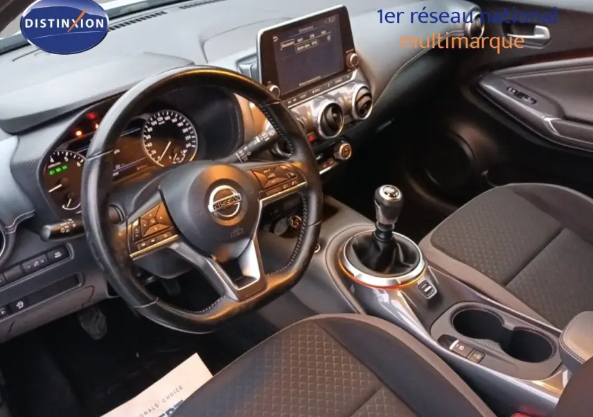 Vue intérieure côté conducteur du Nissan Juke 2020, tableau de bord noir avec volant cuir et levier de vitesse manuel.