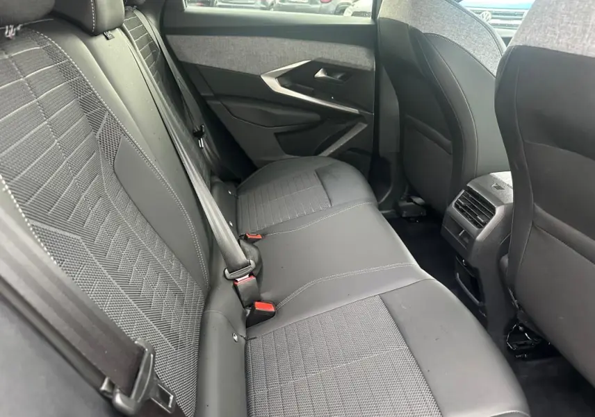 Vue intérieure côté droit des sièges arrière gris foncé du Peugeot 3008 Hybrid 136 e-DCS6 Allure 2025 avec ceintures de sécurité visibles.