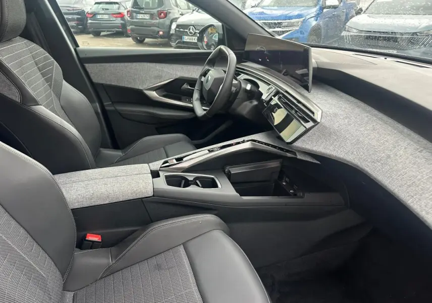 Vue intérieure côté conducteur du Peugeot 3008 Hybrid 136 gris 2025, avec tableau de bord moderne et sellerie mixte tissu-cuir.