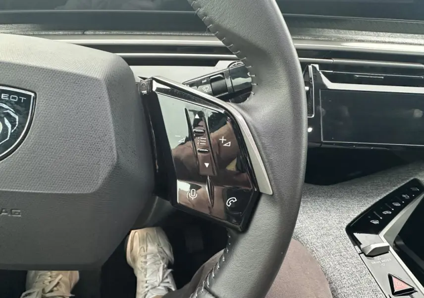 Gros plan sur le volant de la Peugeot 3008 Hybrid 136 e-DCS6 Allure 2025, montrant les commandes multifonctions côté gauche.