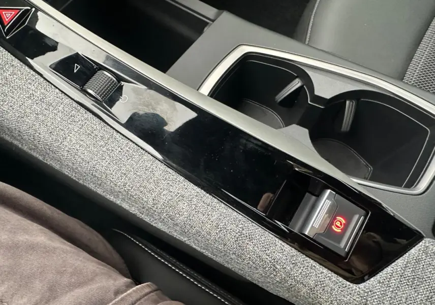 Vue rapprochée de la console centrale grise du Peugeot 3008 Hybrid 2025 avec frein de parking automatique lumineux.